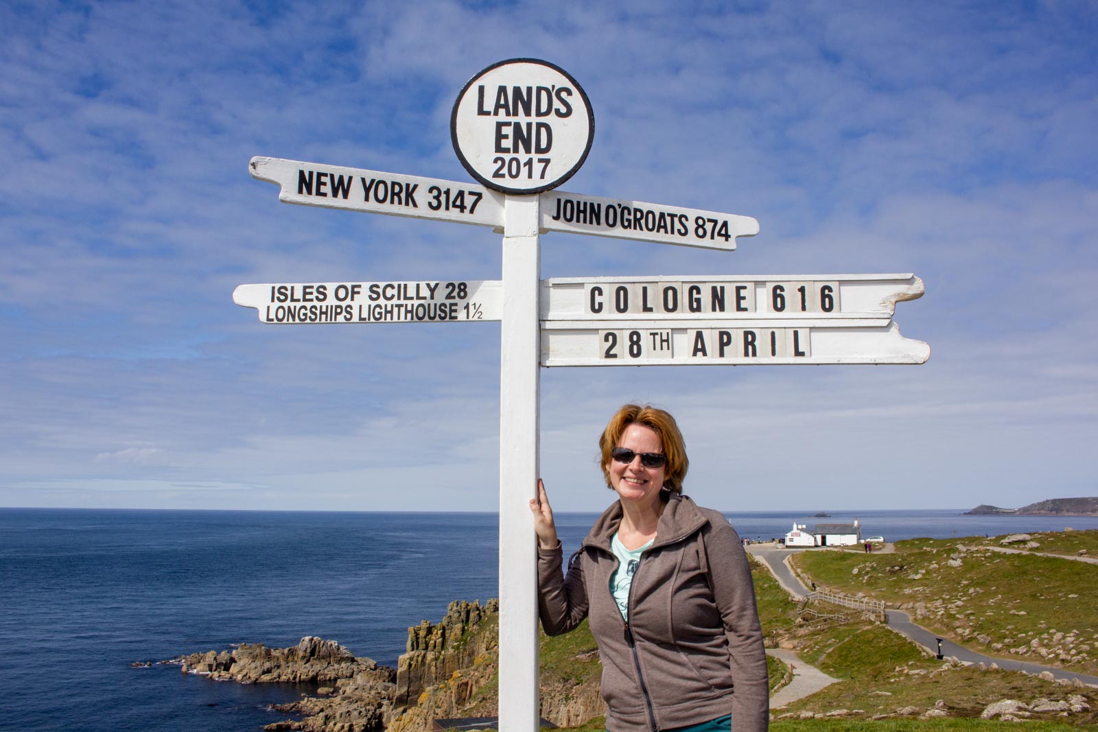 Alleine am Richtungsweiser von Land's End mit Schildern für New Yrk, John O'Groats, Isles of Scilly und Cologne