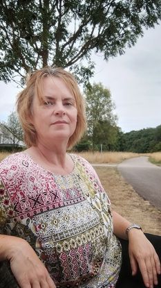 Selbstportrait Rebecca sitzend auf Bank in die Ferne schauend